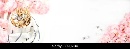Easter banner with Easter eggs on wooden background. Pink spring flowers on wooden table. Copy space. Stock Photo