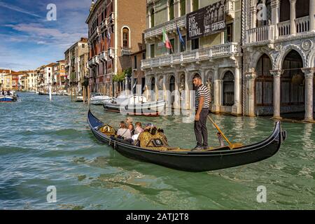 A gondolier taking tourists for a gondola ride past the Ca' d'Oro a Gothic Palace ,along The Grand Canal ,Venice ,Italy Stock Photo