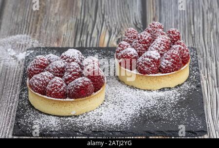 Delicious raspberry mini tarts on wooden background. Food photography Stock Photo