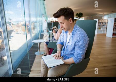 New Helsinki central library Oodi interior. Light and spacious modern scandinan architecture. Bookshelves, working space. Man reading at the window Stock Photo