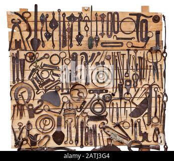 Collection of old forged objects on a wooden stand, on a white background Stock Photo