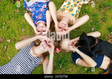 Girls of different age lying together on a moss in a summer forest enjoying summer holidays outdoor Stock Photo