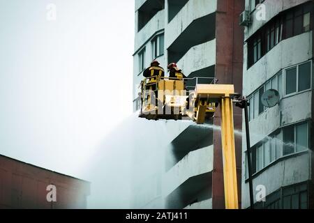 25 October 2019 two firefighters on a crane extinguish a fire. Chisinau, Moldova Stock Photo