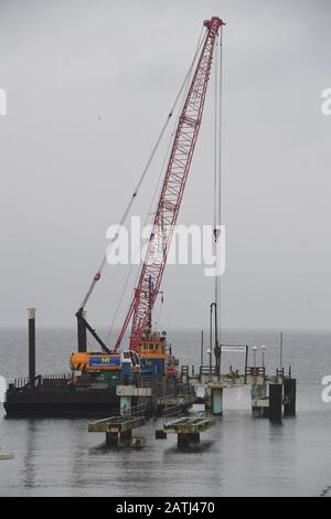 Koserow, Germany. 03rd Feb, 2020. A mobile crane is used to dismantle the pier built in 1993 in the Baltic resort of Koserow. A new pier is to be built by August 2020. It should also rise about 280 metres into the sea, but look completely different from other sea bridges from the Baltic Sea and be barrier-free. According to the plans, the special features are, in addition to a wave appearance in the top view, an almost square bridgehead with a bell tower. The new building is to cost 7.4 million euros. The construction is financed with the help of EU funds. Credit: Stefan/dpa/Alamy Live News Stock Photo