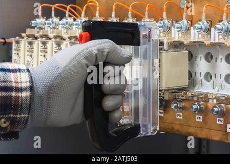 Electricians hand installs breakers in an electrical switchboard close-up Stock Photo