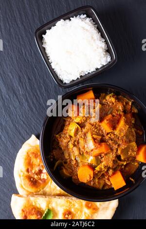 Oriental food concept spicy grounded or minced beefs masala curry with naan bread and rice on black slate background Stock Photo
