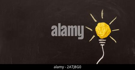 Creative new idea. Innovation, brainstorming, inspiration and solution concepts. Light bulb with crumpled paper on blackboard background. Stock Photo