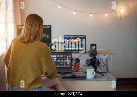 Backside editor video woman working with footage video on a laptop and computer pc in the house studio of lifestyle freelance Stock Photo
