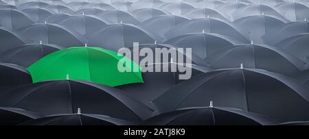 Different and standing out of the crowd yellow umbrella. Concept of leader with many blacks umbrella. Stock Photo