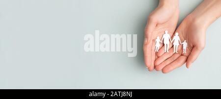 Hands with cut out paper silhouette on table. Family care concept. Stock Photo