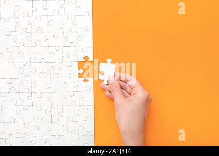 Hand put the last piece of jigsaw puzzle. Complete the mission. Business concept. Stock Photo