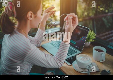 Young woman freelance use laptop editing video footage in the coffee shop this is the lifestyle of the content creator Stock Photo