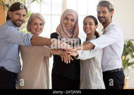 Portrait of smiling diverse employees stack hands together Stock Photo
