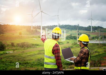 Two engineering work with together at the windmill farm Stock Photo