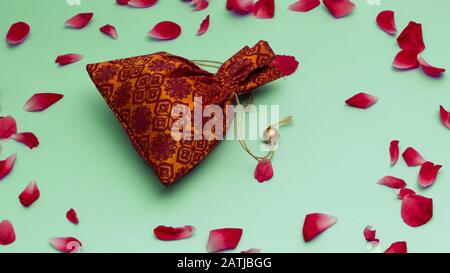 Close-up gift pouch with rose petal on green background, love concept for valentines day, Happy and romantic moment. Stock Photo