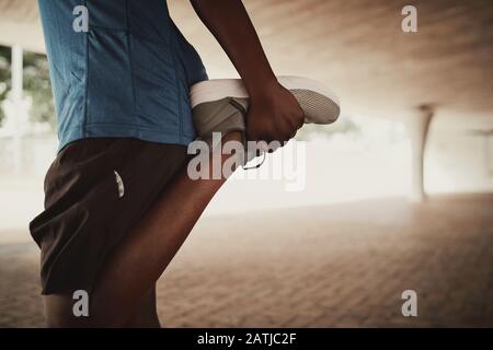 Close up of sporty male stretching his legs muscles before run on street Stock Photo