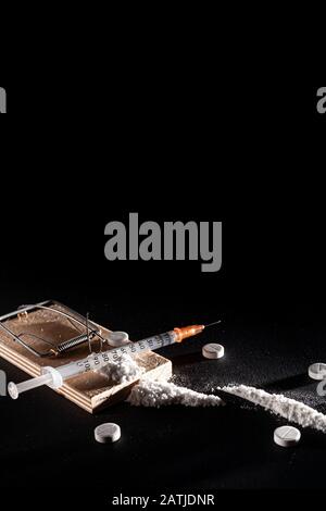 Addiction and dependence on drugs. A stock photo of a mousetrap with a bait in the form of various drugs and medicines. Stock Photo