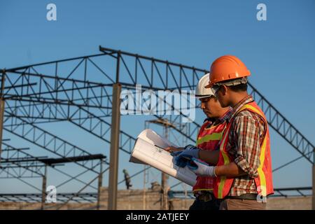Construction work, Two engineers use blueprint analysis construction at the construction site Stock Photo