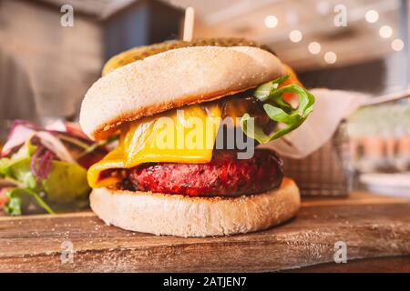 Melted cheese  on a portobello mushroom and beetroot and bean vegetarian burger in a bun, on a wooden serving board. Stock Photo