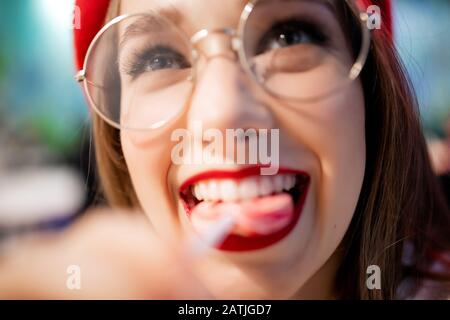 Concept caries and harm is danger to tooth enamel. Young girl eating sweet sticky stick in France cafe in red beret and glasses Stock Photo