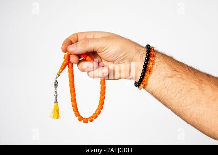 Man holding rosary made of amber in hands on isolated white background Stock Photo