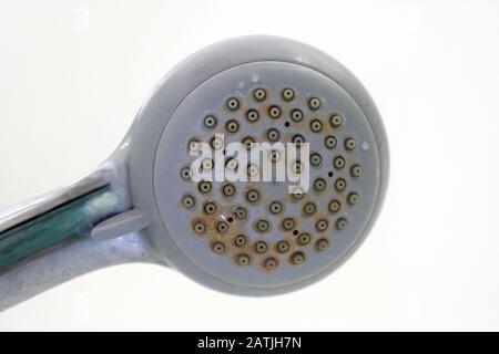 Old shower head with plaque. Dirty plastic shower head. Limescale coating on plumbing. Stock Photo