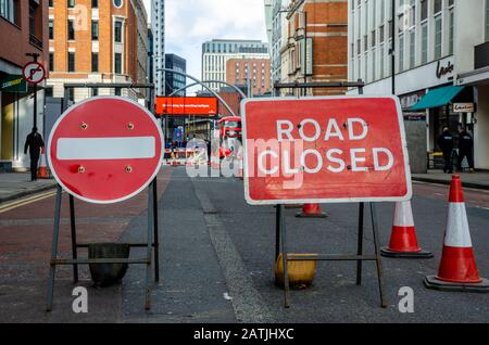 A road in London is closed for repairs. Red road signs and traffic cones block the way. Stock Photo