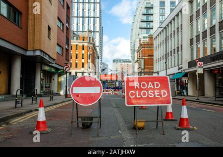 A road in London is closed for repairs. Red road signs and traffic cones block the way. Stock Photo