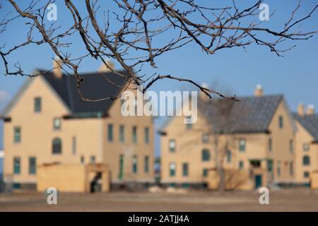 A view of the empty military residences along Officer's Row at Fort Hancock. The focus in this image is on the tree branches, with the houses blurry i Stock Photo