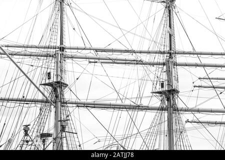 Monochrome image of mast with rigging and rolled up sails of old polish sailing ship Dar Pomorza Stock Photo