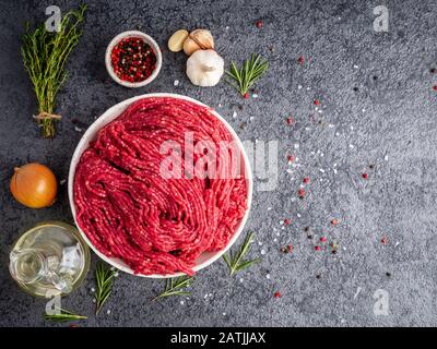 Mince beef, ground meat with ingredients for cooking on dark gray background with copy space, top view Stock Photo