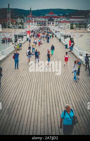 Tourists walking on wooden Sopot Pier in Gdansk Bay viewed in spa house direction Stock Photo