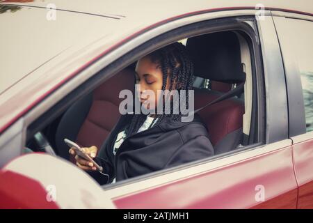 portrait of an African-American teenaged girl sitting in a car a texting