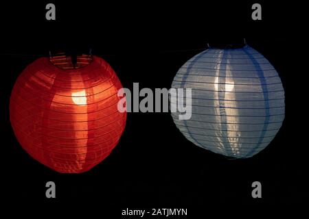 Chinese lanterns illuminated at night, red and blue lantern made of fabric and wire with light bulb inside Stock Photo
