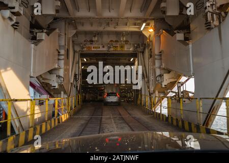 Bow doors are open and cars are driving inside a big car ferries car deck in the port of Turku Finland in the evening Stock Photo