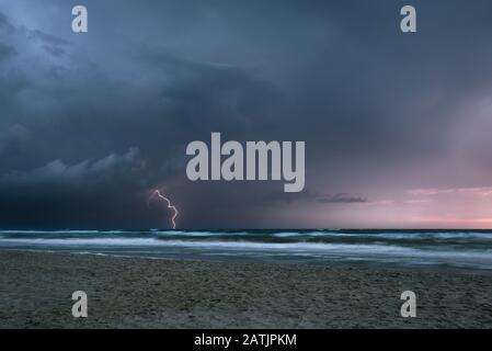 Dramatic view of a thunderstorm with lightning strike in the sea at dusk Stock Photo