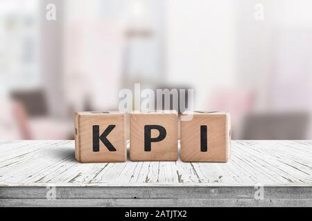 KPI word on a wooden sign in a bright environment with furniture in the background Stock Photo