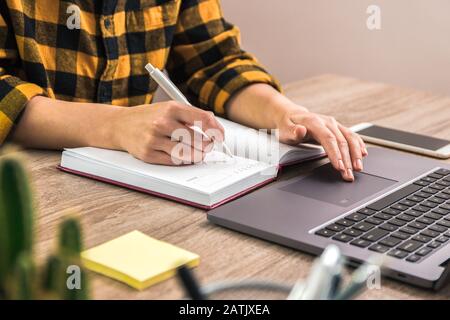 the study is power. close up hands of a businesswoman, student or freelancer in yellow shirt making notes in her notebook Stock Photo