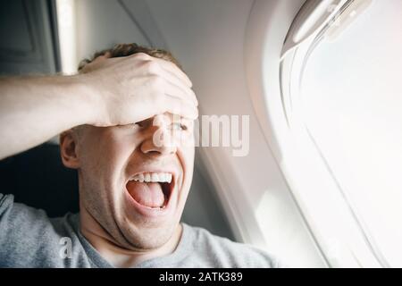 Passenger man in plane clutches his head, afraid of heights and flight. Scream and cry expression Stock Photo