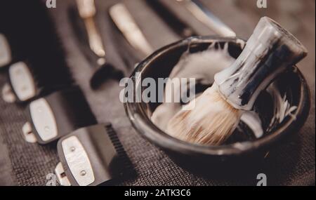 Brush for applying foam on beard man shaving with razor in barbershop background of tools Stock Photo