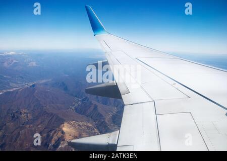 Photo from window of wing airplane flying over Alps mountains. Travel concept Stock Photo