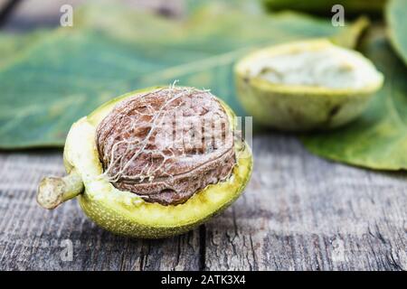 Fresh walnuts in a green shell on an old wooden table. Nuts in green shells. Harvest walnuts. Stock Photo