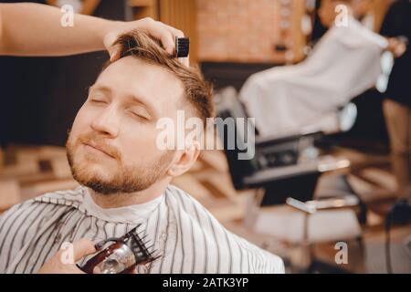 Close-up of barber shaving beard to man in barbershop Stock Photo