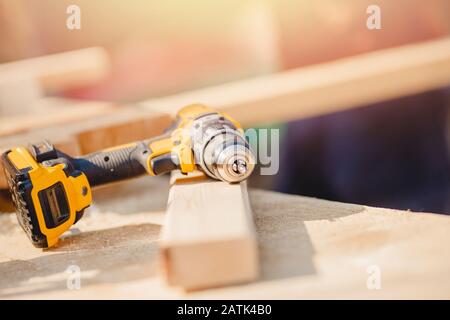 Electric mobile tool screwdriver for repair and tightening bolts in wooden beam Stock Photo
