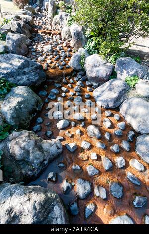Hot spring (Jigoku), multi-colored volcanic creek with stones in Kannawa district in Beppu, Japan. Stock Photo