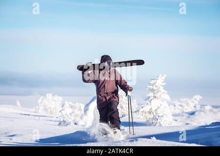 Skier rises up slope with skis against backdrop of Alps mountains. Concept freeride Stock Photo