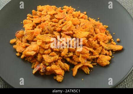 Close up of crispy fried red pepper pieces ingredient on black plate Stock Photo