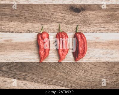 Decoration of chili peppers on wodden board. Three Bhut jolokia on wooden background Stock Photo