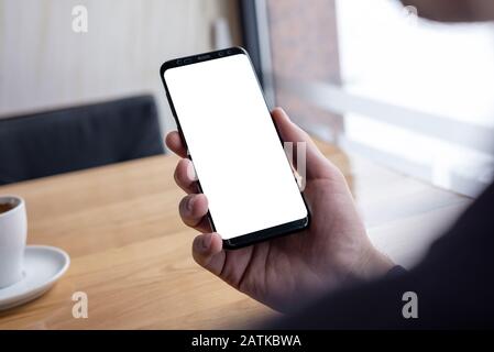 Mockup image of man hand holding modern black phone with thin edges Stock Photo