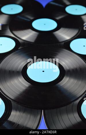 pile of old black vinyl records with blank cyan labels on blue background Stock Photo